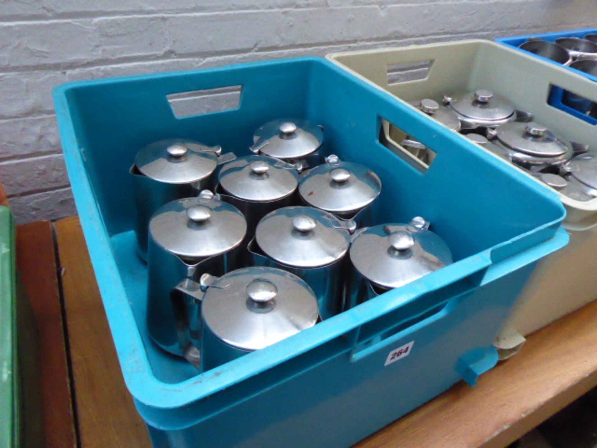 Green plastic stacking box with 8 stainless steel teapots