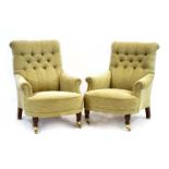 A pair of contemporary button upholstered lounge armchairs on beech feet with castors