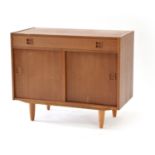 A 1960's Danish teak cabinet, the single drawer with integral handles over a pair of sliding doors,