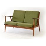 A 1960's Danish teak two-seater sofa with loose green cushions, on circular tapering legs, l.