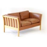 A Danish tan leather two seater sofa with an exposed beech frame,