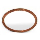 An Arts and Crafts hammered copper wall mirror of oval form,