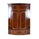 A 19th century mahogany and crossbanded hanging corner cabinet of bow-fronted form,