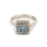An 18ct white gold cluster ring set emerald cut (?)aquamarine within a border of small diamonds,
