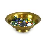 A Chinese brass 'singing' bowl containing a group of Victorian and later glass marbles