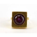 A 1970's yellow metal dress ring set amethyst coloured stone within a square shaped setting,
