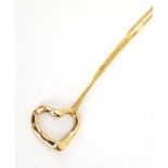 An 9ct yellow gold fine curb link necklace suspending an openwork heart shaped pendant set small