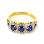 An 18ct yellow gold ring set three oval sapphires and small diamonds in halo-type settings,
