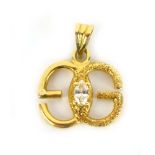 A yellow metal pendant in the form of a pair of entwined 'G's' set centrally with a marquise cut