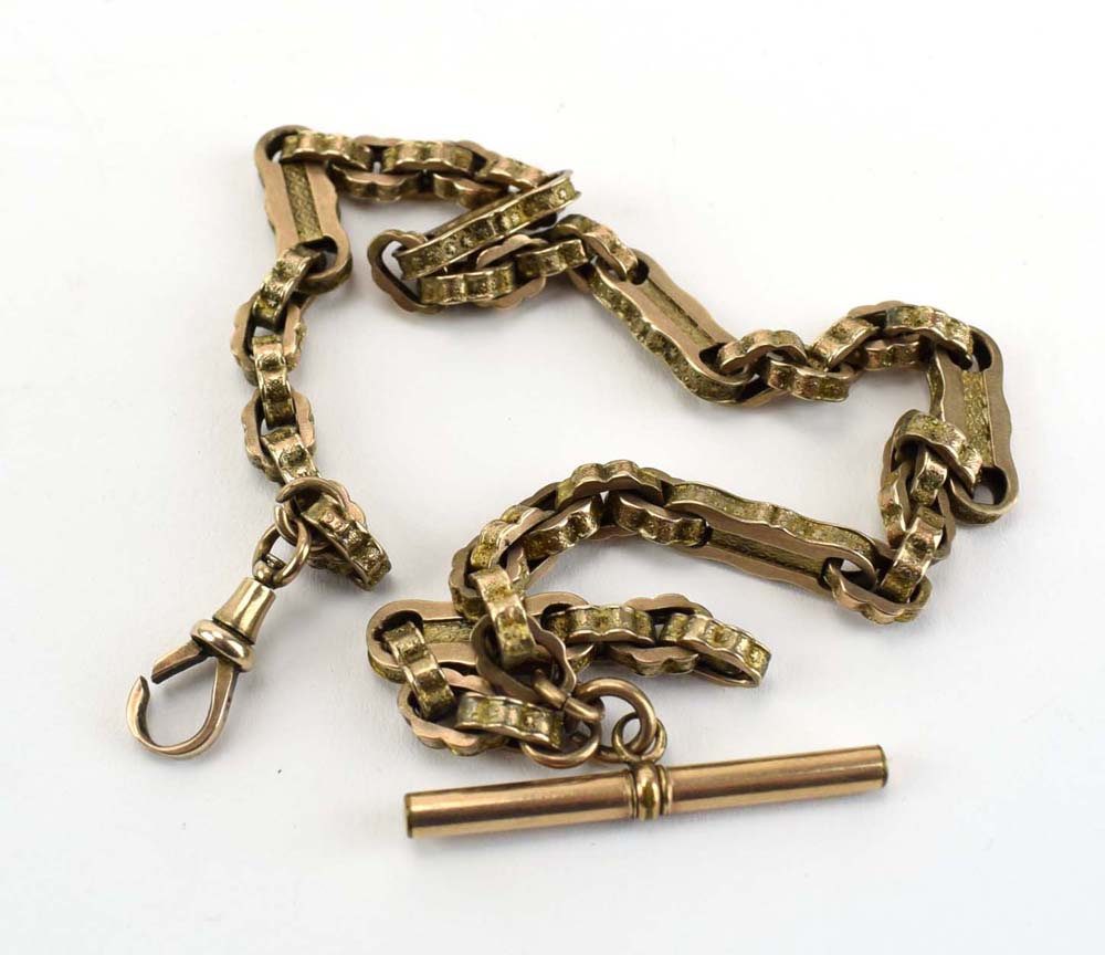 A yellow metal fancy link watch chain, lobster clasp stamped '9c' suspending a gold plated t-bar,