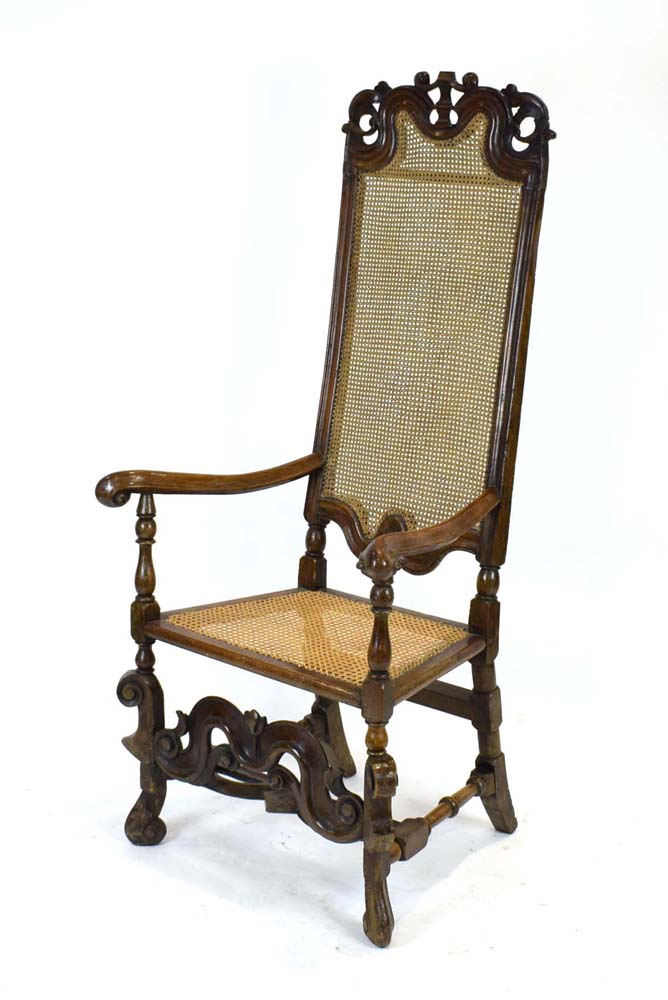 A 17th century walnut highback elbow chair with a scrolled arms,