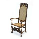 A 17th century walnut highback elbow chair with a scrolled arms,