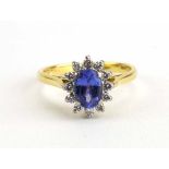 An 18ct yellow gold cluster ring set oval tanzanite within a border of small diamonds,