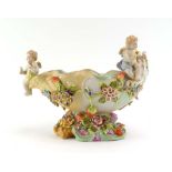 An early 20th century table centre of shell form relief decorated with putti within a florally