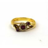 An 18ct yellow gold ring set three rubies and small diamonds in a crossover cluster setting,