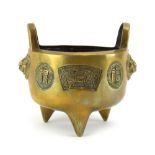 A Chinese brass two handled censer with grotesque handles and decorated with character marks,