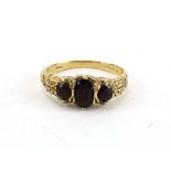 A 9ct yellow gold ring set three graduated garnets in a scrolled setting, ring size L, 2.