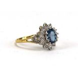 A 9ct yellow gold cluster ring set oval blue stone within a flowerhead diamond set border,