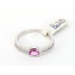 An 18ct white gold ring set oval pink sapphire in a rubover setting,
