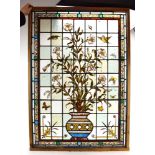 A stained glass and leaded panel depicting birds around a vase of flowers,