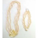 A three strand baroque pearl necklace with mother of pearl flowerhead clasp,