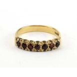 A 9ct yellow gold half eternity ring set seven garnets, ring size V, 3.