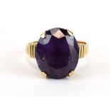 A yellow metal ring set oval amethyst coloured stone in a raised four claw setting, ring size P, 5.