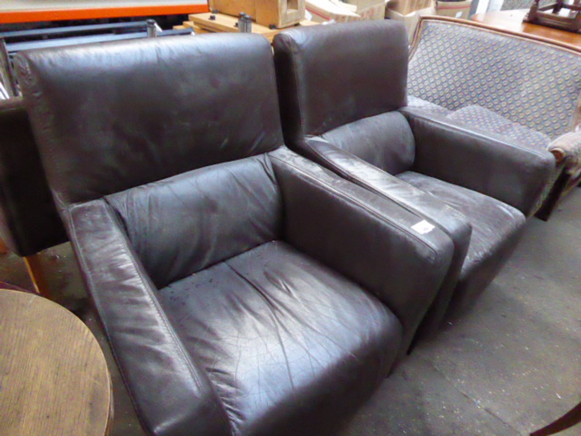 2 brown leather chairs with 1 stripy and 1 black cloth chair