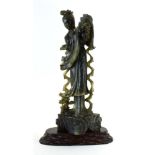 A Chinese carved green soapstone figure modelled as a traditional female carrying a vase of flowers,