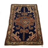 A Kazak rug, the cobalt blue field with a central pale pink geometric panel within an ivory border,