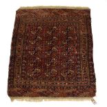 A Turkoman rug having fifteen medallions within a claret and navy field,