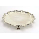 A silver salver of circular form on three scrolled feet, Mappin & Webb, Sheffield 1924, d.