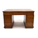 An early 20th century oak twin pedestal partner's desk having a tooled tan leather surface above an