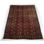 A Turkoman carpet, with four rows of eleven cream medallions within a claret ground,
