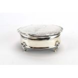 An early 20th century silver ring box of oval form on outswept feet, Birmingham hallmarks rubbed, w.
