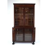 An Empire-style mahogany two stage cabinet bookcase having two pairs of glazed doors and lion's