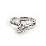 A white metal crossover ring set brilliant cut diamond in a three claw setting,