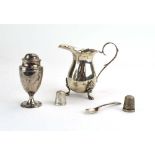 A mixed parcel of silver comprising a cream jug, two thimbles, a salt spoon and a pepper,