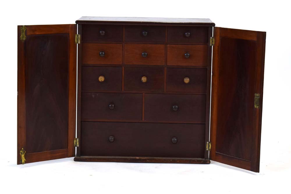 A 19th century mahogany table cabinet, the pair of doors enclosing an arrangement of twelve drawers,