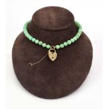 A continuous pale green jade bead necklace suspending a 9ct yellow gold heart shaped locket, bead d.