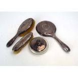 An early/mid 20th century silver mounted three piece dressing table set and a similar powder,