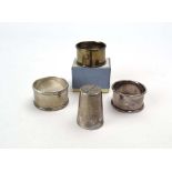 Three silver napkin rings, various dates and makers, together with a small German metalware beaker,