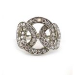 A platinum ring in the form of three entwined loops and set small brilliant cut diamonds,