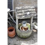 Concrete garden wishing well with several terracotta plant pots