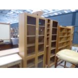A glazed beech four door bookcase, a CD rack and an open fronted bookcase