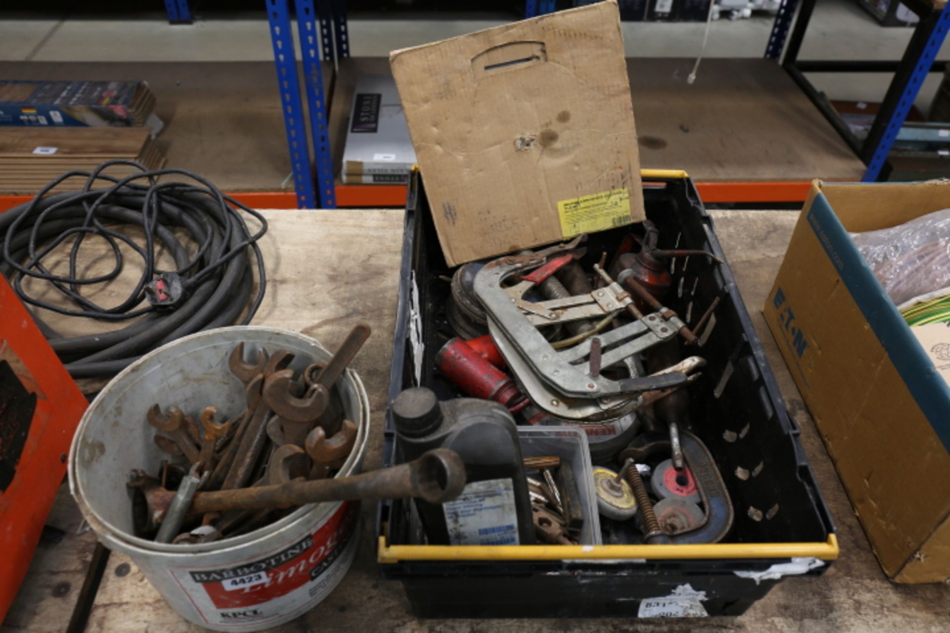 Black crate containing oil cans, taps, dies, grinding wheels and a small bucket of spanners
