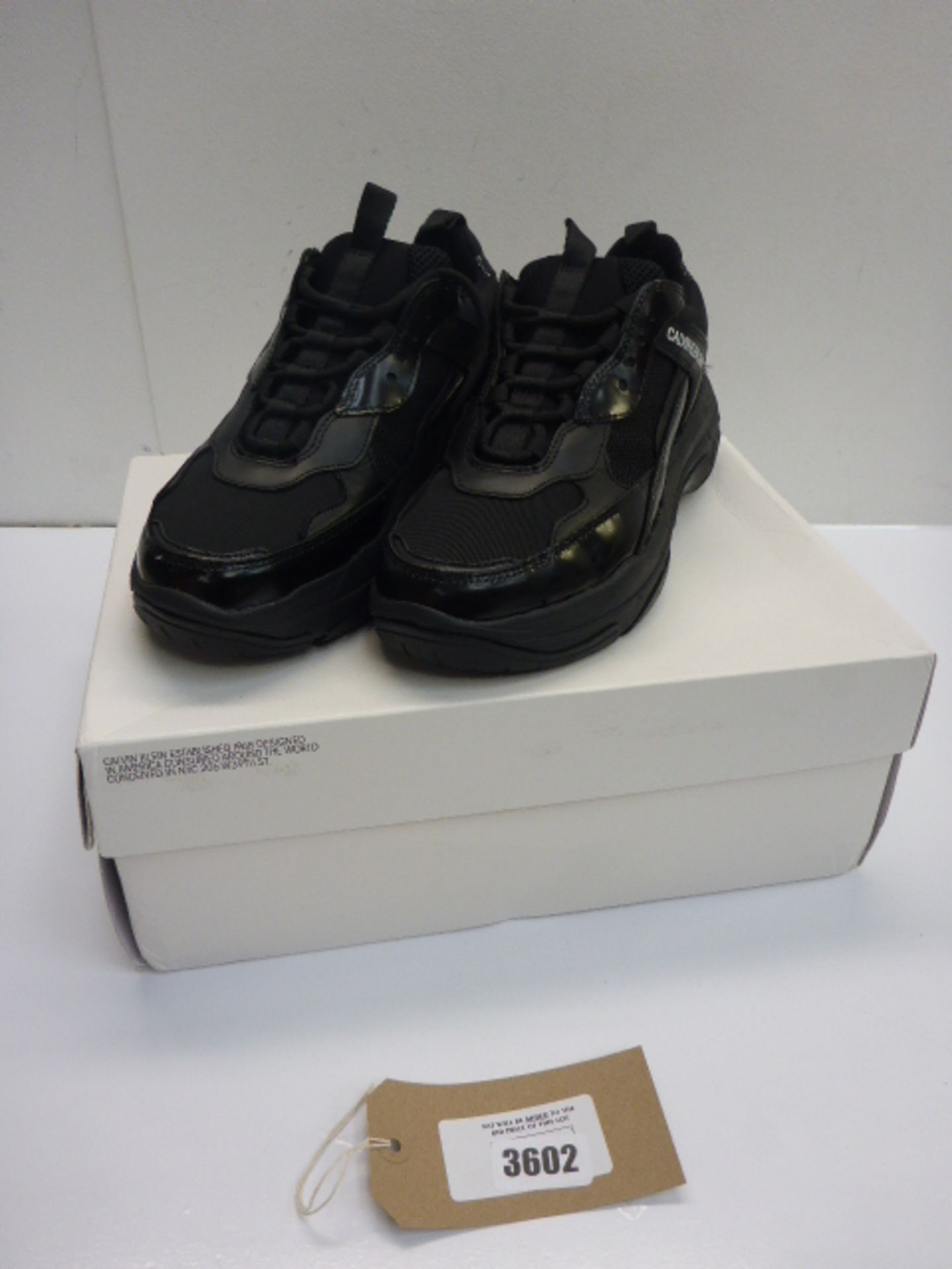 A pair of Calvin Klein Jeans in patent black/leather trainers UK 9