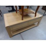 An oak finish coffee table with two drawers and shelf under