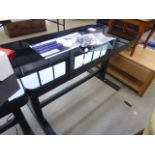 An adjustable black glass work desk