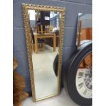 5246 A narrow bevelled rectangular mirror in an ornate gilt frame